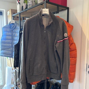 Moncler Zip Up Cardigan  - Grå Moncler Zip Up Cardigan i väldigt bra skick, general wear. Som ny efter en tvätt! Storlek L passar M, nypris 5500 mitt pris 2000kr men tar emot rimliga bud! Över 250 deals gjorda med massvis av refs att visa, bara att skriva vid frågor eller finderingar!