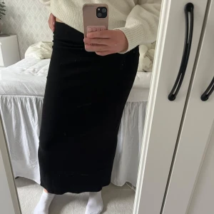 Svart lång kjol - Säljer en fin lång svart kjol med ribbade kanter och slits💕Jätteskönt material med mycket stretch, kjolen sitter löst ner till så den drar ingenting när man går, man kan gå fritt utan att den sträcker sig efter benen, Jättefin och passar till allt☺️