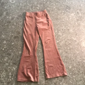 Rosa velourbyxor med utsvängda ben från Lindex - Säljer ett par mjuka och sköna rosa velourbyxor från Lindex med utsvängda ben. Byxorna har resår i midjan och är perfekta för en avslappnad stil. Passar barn i storlek 146/152.