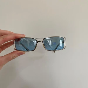 solglasögon med blåtonade glas - Snygga solglasögon från Polaroid med rektangulära blåtonade glas och silvriga metallbågar. Snygga nu till vår och sommar🌸