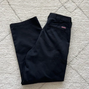 Svarta byxor från Dickies - Säljer ett par klassiska svarta byxor från Dickies. De har en rak passform och är tillverkade i slitstarkt material. Perfekta för en stilren look. Byxorna har praktiska fickor och en diskret logga på baksidan.