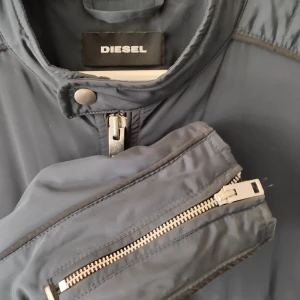 Diesel J-Quad jacka - Mörkblå lättfodrad jacka från Diesel. Stilren med detaljer i silver. Bild 2 och 3 mest sann till färgen.