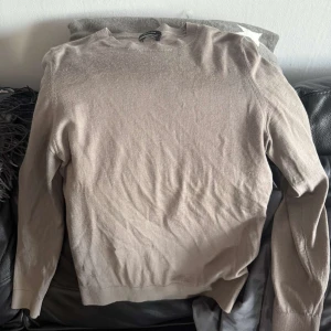 Massimo dutti tröja - Säljer en stilren beige långärmad tröja från Massimo dutti. Tröjan har rund halsringning och är tillverkad i ett tunt, mjukt material som passar perfekt för lager-på-lager. Enkel och tidlös design som funkar till många outfits.