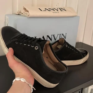 Lanvin skor - Snygga svarta sneakers från Lanvin med vit sula och snörning. Skorna har en stilren design med rund tå och är tillverkade i skinn och mocka. Perfekta för en trendig look, storlek 42