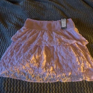 Ljuslila volangkjol med broderade blommor - Supersöt ljuslila kjol med volanger och broderade blommor. Helt ny med lappar, perfekt inför sommaren! Från Vero Moda, nypris ca 450 mitt pris 250kr 🥰