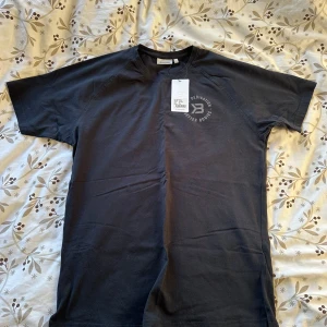 Svart Gym T-shirt från Better Bodies - Säljer en svart t-shirt från Better Bodies i modellen Gym Tapered Tee. T-shirten har rund halsringning, korta ärmar och en liten logga tryckt på bröstet. Perfekt för träning eller gymmet.