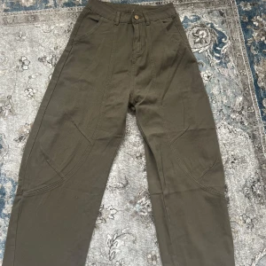 Olivgröna jeans med fina markerade sömmar, pris kan diskuteras - Säljer ett par snygga olivgröna jeans med raka ben och markerade sömmar. Byxorna har medelmidja, fickor fram och bälteshällor. Perfekta för en avslappnad och trendig stil.