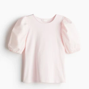 Ljusrosa blus med puffärmar - Säljer en söt ljusrosa blus med puffiga kortärmat . Blusen har en rund halsringning och är tillverkad i ett mjukt material.