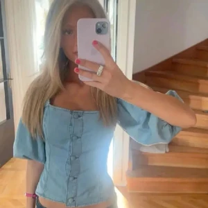 Jeans topp hm  - Snygg blå korsett i jeansmaterial med knappar framtill och puffiga trekvartsärmar. Perfekt för en trendig look. Strl M men den är insydd, be om mått 