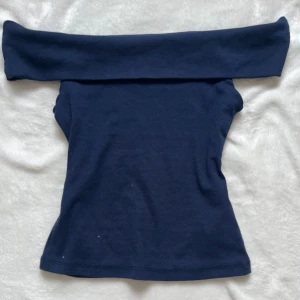 Mörkblå offshoulder topp - Säljer en mörkblå offshoulder topp med tight passform som tyvärr inte har kommit till användning. Toppen är croppad och har en stilren design utan mönster. Perfekt för dig som gillar en enkel men snygg look.