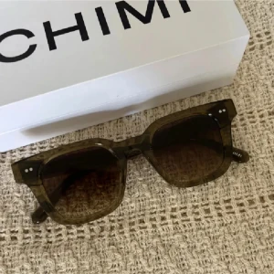 Chimi Solglasögon 04 - Snygga solglasögon från Chimi med en fyrkantig form och transparent brun båge. Perfekta för att ge en stilren touch till din look. Kommer i originalförpackning.