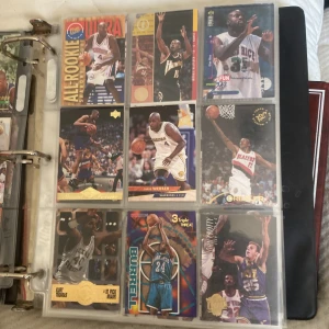 Samling av basketkort i pärm - En pärm fylld med olika basketkort från NBA. Kort med spelare i olika positioner och lag, inklusive rookiekort och specialutgåvor. Perfekt för samlare eller basketentusiaster som vill utöka sin kollektion. Kom med bud!