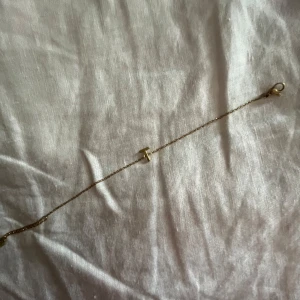 Guldarmband med T-berlock - Snyggt och stilrent armband i guld med en tunn kedja och en minimalistisk T-formad berlock i mitten. Perfekt för dig som gillar personliga detaljer och enkel design. Kommer i en fin ask, redo att ges bort eller användas direkt. Armbandet är bara några månader och inte hunnit bli så använt pris kan diskuteras🫰🏼🥹🥹