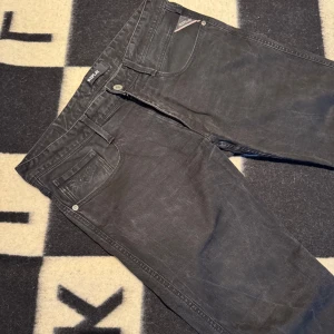 Svarta Replay jeans straight fit - Säljer ett par svarta jeans från Replay med klassisk femficksdesign och raka ben. Jeansen har diskreta sömmar på bakfickorna och en snygg tvättad finish. Perfekta för dig som gillar en enkel och stilren look. Ingen aning om storlek men skulle gissa på 30/30
