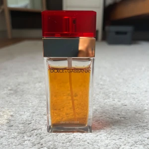 Dolce & Gabbana Eau de Toilette 50ml - Dolce & Gabbana Eau de Toilette i 50 ml flaska. Flaskan är rektangulär i glas med guldigt band och röd plastkork. Parfymen kommer i en lyxig röd sammetsask med gulddetaljer. Använd några gånger. Nypris 1356kr