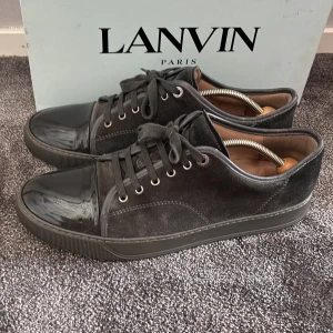 Svarta sneakers från Lanvin i mocka - Snygga svarta sneakers från Lanvin med ovandel i mjuk mocka och glansig tå i skinn. Skorna är i otroligt fin skick. Tillkommer box och snören. 