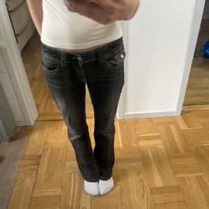 Svarta bootcut jeans - Säljer ett par grå/svarta bootcut jeans från gina young i storlek 164. Byxorna är uppsprättade längst ner. Jag är 173cm lång