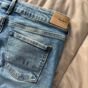 Bootcut Pepe Jeans, ljusblå - Ljusblå bootcut jeans från Pepe Jeans i modellen Piccadilly. Jeansen har midwaist, klassiska fem fickor. Tillverkade i mjukt denim med Pepe Jeans-logga på bakfickan och läderpatch i midjan. Helt nya och oanvända.
