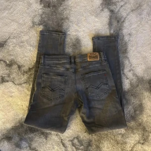 Grå Replay jeans med raka ben - Säljer ett par grå jeans från Replay med klassiska bakfickor och snygg tvätt. Jeansen har raka ben och en stilren look, perfekta till sneakers eller boots. Märkespatch bak i midjan och diskreta detaljer.