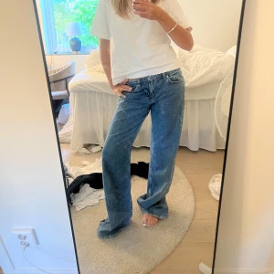Wida lågmidjade jeans nakd  - Säljer ett par blå jeans från NA-KD med riktigt snygg wide fit och klassisk femficksdesign. Jeansen har normal midja och raka, vida ben som ger en avslappnad vibe. Perfekta till sneakers eller boots för en chill look. Färgen är en som första bilden utan spegeln är smutsig