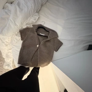 Brun stickad kofta från Zara - Kortärmad, brun  stickad kofta från Zara med stor krage och en knapp framtill. Koftan har en loose på mig passform och är perfekt att slänga över ett linne. Mysig och trendig för lager-på-lager-stil. Använd 1 gång 