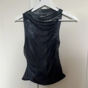 Svart mesh linnetopp - Svart mesh asymmetrisk linnetopp från Pull&Bear i storlek S. Ej genomskinlig, använd en gång!