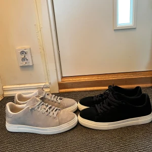 Selected homme mocka sneakers / skor - Två par ingår!  Extremt fina mocka skor där ena skon har svart mocka färg med vit sula och den andra grå mocka färg med vit sula. Bägge paren är i storlek/ size 45 / UK 11 / US 12 Skorna är i extremt bra skick, den svarta har använts mindre än den gråa. Har kvar original förpackning till de gråa paren Skicka meddelande vid några funderingar  Kolla gärna även in mina andra annonser