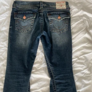 True Religion bootcut jeans  - Säljer ett par blå bootcut jeans från True Religion med slitningar på knäna och fina detaljer. Sjukt snygg tvätt. Jeansen e lowwaist. 