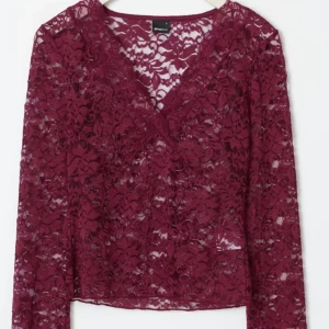 Vinröd spetsblus med v-ringning - Vinröd långärmad blus i genombruten spets med v-ringad hals och figurnära passform. Blusen har fina spetsdetaljer och är perfekt för dig som vill sticka ut lite extra. Snygg att matcha med både jeans och kjol.