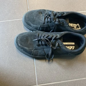 Svarta cykelskor från Leatt i mocka - Svarta cykelskor från Leatt i mocka med klassisk snörning och låg profil. Skorna har en gummisula med mönster för extra grepp och en stilren, enkel design som passar till det mesta. Perfekta för dig som gillar en clean och sportig look.