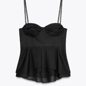 Svart korsett-topp med volang - Supersnygg svart korsett-topp med tunna dubbla axelband och volangig nederdel. Toppen har draperad byst och markerad midja som ger en riktigt trendig siluett. Perfekt för att lyfta vilken outfit som helst.