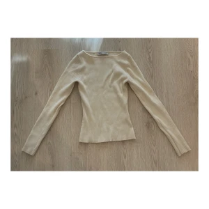 Beige ribbad långärmad tröja Zara - En beige ribbad långärmad tröja från Zara. Tröjan har en slim passform och är tillverkad i mjukt, stretchigt material som sitter snyggt på kroppen. Perfekt basic att ha i garderoben för en clean och stilren look. Storlek M men skulle säga att den är mer som S.