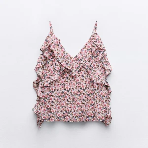 Blommig volangtop med smala axelband - Supersöt blommig linnetopp med volanger och smala axelband. Toppen har v-ringning och är perfekt för varma dagar. Färgerna går i rosa, vit och grön med små blommor över hela tyget. Lätt och luftig känsla.