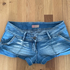 lowwaisted vintageshorts - Snygga blå jeansshorts från Soul Cal med slitna detaljer och kontrastsömmar. Shortsen har låg midja, klassiska fickor fram och bak samt en cool gul dragkedja på ena bakfickan. Perfekta för sommaren och ger en avslappnad vibe.  står att de är en size 10 men som preferens är jag en M och dom passar mig