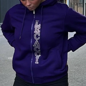 Lila hoodie med strassfjäril från Lecacci - Säljer en lila hoodie från Lecacci med dragkedja och huva. Framsidan har Lecacci-loggan i stora strasstenar och baksidan pryds av en stor glittrig fjäril. Hoodien har fickor på sidorna och är i mjukt fleecematerial. 