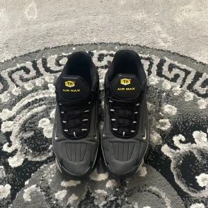 Nike Air Max TN  - Svarta Nike Air Max TN sneakers med coola detaljer och tydlig Tn-logga på plösen och hälen. Snygg design med silvriga swoosh och synlig Air Max-dämpning i sulan. Skorna har snörning och är tillverkade i syntetmaterial och textil.