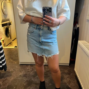 Blå jeanskjol från Zara - Säljer en snygg blå jeanskjol från Zara i storlek S. Kjolen är kort med klassiska fickor fram och bak samt knapp och dragkedja. Perfekt för dig som gillar en chill och trendig stil.