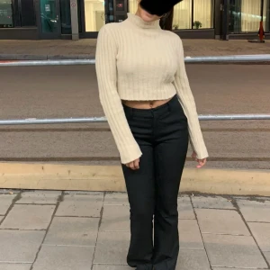 Beige croppad polotröja stickad - Superfin croppad polotröja i beige med ribbad stickning och långa ärmar. Tröjan har en hög krage och är gjord i mjukt stickat material som känns skönt mot huden. Perfekt till svarta jeans eller kjol för en chill och snygg look.