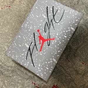 Nike Air Jordan 4 - Säljer ett par Nike Air Jordan 4 sneakers i svart mocka med röda och grå detaljer. Skorna har klassisk mesh på sidorna, vita plastdetaljer och röd Jumpman-logga på plösen. Snygg och ikonisk siluett som sticker ut med sin unika design och färgkombination.