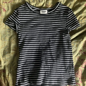Randig svartvit t-shirt från Weekday - Åtsittande svart t-shirt från Weekday med vita horisontella ränder. Modellen är kortärmad med rund halsringning och har en ribbad struktur i tyget. Säljer då den tyvärr är för liten för mig. 