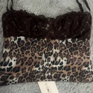 Leopardmönstrad korsett från SHEIN - Snygg korsett-topp från SHEIN med leopardmönster i bruna och svarta toner. Överdelen har mörkbrun spets och justerbara axelband. Baksidan har hakknäppning för extra stöd. Perfekt för dig som vill sticka ut med coola detaljer och djurprint.