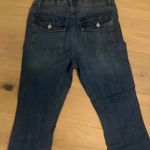 Mörkblå bootcut jeans - Snygga mörkblå jeans med bootcut passform och låg midja från Junkyard. Storleken är S/M och är justerbara, använda en gång. 