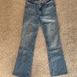 Lågmidjade bootcut jeans med lätt skimmer - Snygga lågmidjade jeans med lätt silverfärg på benen. Kan ses på bilder. Har sytt dom mer lågmidjat vilken visas på bild, det syns inte när man har jeansen på sig. Jättefina i övrigt. Är små i storleken och passar bra på mig som vanligtvis är 36 i byxor och 163 cm.