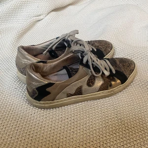 Sneakers med ormskinnsmönster och metallicdetaljer - Säljer ett par ascoola skor i äkta ormskinn och läder. Varan har använts med väldigt sparsamt och har därför inga större skador. De är i storlek 38 ❤️
