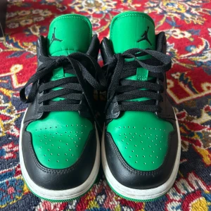 Nike Air Jordans 1 Low  - Säljer ett par Nike Air Jordans Low med grön ovandel, svarta detaljer. Skorna har klassisk Air Jordan-logga på hälen och svart snörning. Som nya använt 1 gång och Perfekta för dig som vill sticka ut med färg och stil. 