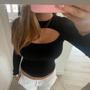 Svart ribbad långärmad topp med cut-out - Svart  ribbad topp med lång ärm och  cut-out detalj över bröstet. Storlek Xs men strechig så passar S också. Möjligtvis en liten M då jag brukar ha m ibland. 