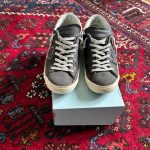 Blåa sneakers från Philippe Model - Säljer ett par blåa Philippe Model sneakers med vita detaljer och svart sula. Skorna har snörning och en ikonisk logga på sidan. Perfekta för dig som gillar stilrena och bekväma sneakers.