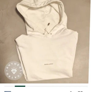 Vit hoodie från Saint Laurent - Supersnygg vit huvtröja med diskret logotyp framtill. Modell Rive Gauche. Inte gulnad, märken eller fläckar. Äkthetsintygad på Tradera. Skick 9/10. Längd ca 70 cm, bredd under arm ca 57 cm. Nypris dryga 8000 kr. 