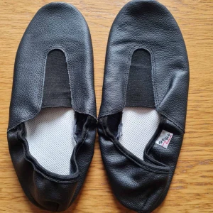 Svarta gymnastikskor i skinn strl 40 - Säljer ett par svarta gymnastikskor i äkta läder i mycket bra skick. De har en enkel design med runt tå och elastisk öppning för enkel på- och avtagning. Perfekta för inomhusaktiviteter och träning.   Storlek 40.  Kan hämtas i Vallentuna.