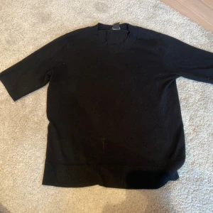 Svart topp från Lindex - En svart topp från Lindex med ribbad nederkant och halvlånga ärmar. Jag har köpt tröjan secondhand.